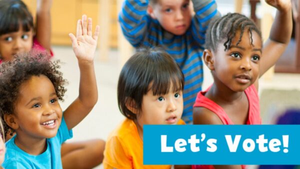 kids raising their hands as they sit together on the floor in a classroom