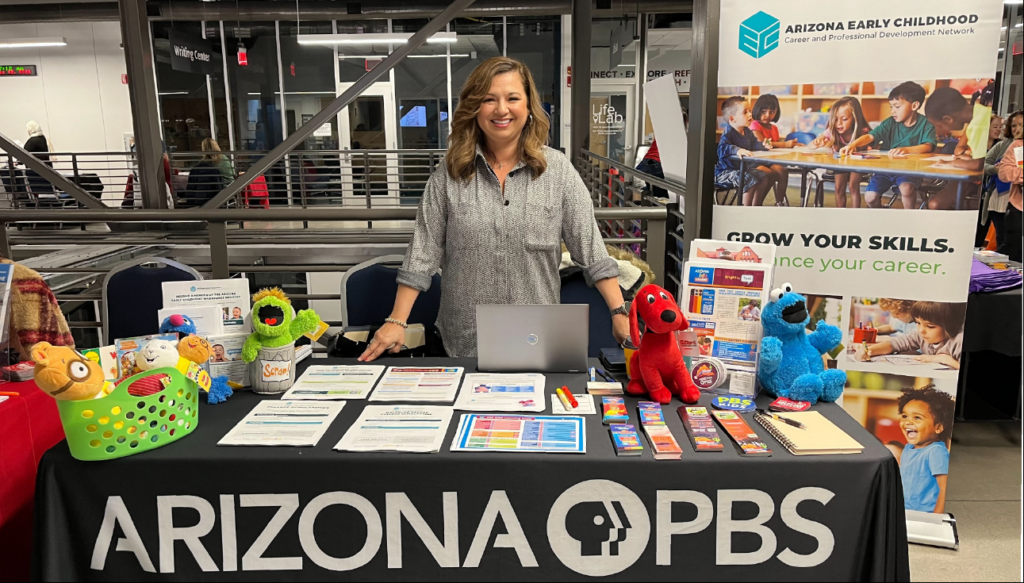 Gloria of Arizona PBS stands at a booth at a local event