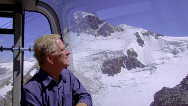 Rick Steves looking out over snow covered mountains
