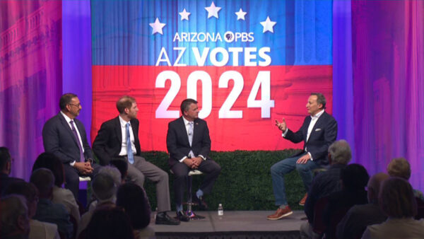 David Becker sits on a stage leading a panel of three guests with a sign behind him reading: Arizona PBS AZ Votes 2024
