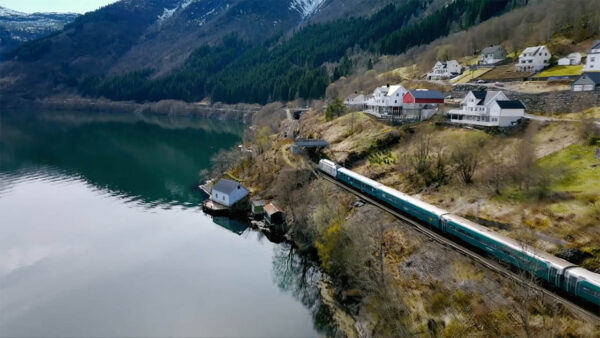 A photo of a train passing by a large lake for Epic Train Journey