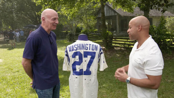 Two men standing in front of an antique jersey for Antiques Roadshow