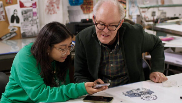 John Lithgow and a student looking at a phone