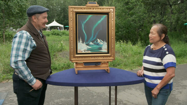 Two people stand around a painting of the Northern Lights