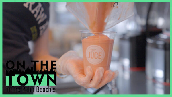 A close-up of a smoothie being poured into a cup labeled 'raw JUCE' by a person wearing gloves.