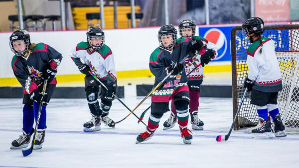 A group of young hockey players energetically playing on an ice rink.