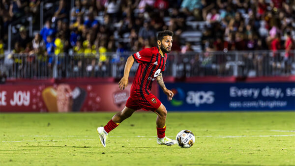 A man playing soccer on a field, showing his skills and passion for the game.