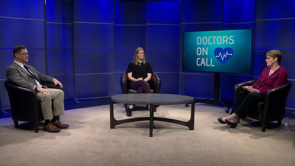 Three people discussing in front of a television