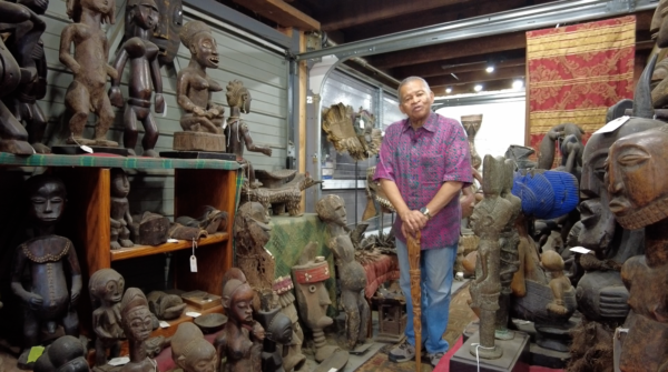 A man stands with his collection of traditional African art