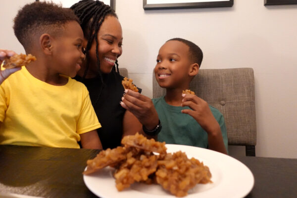 A mom and two sons eat Jamaican coconut drops