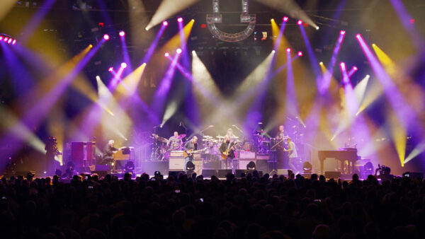 A vibrant concert scene illuminated by purple and yellow lights, creating an energetic and dynamic atmosphere.