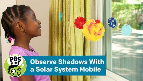 A girl looking at a solar system mobile