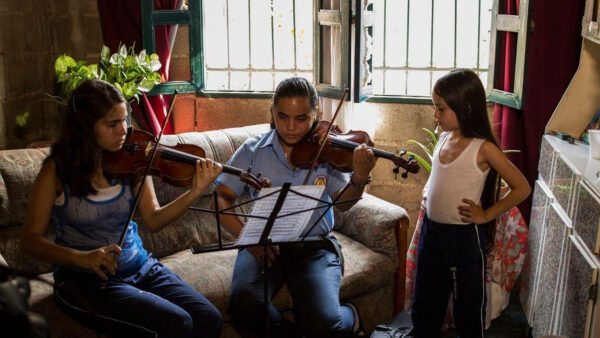 Kids joyfully plays violins together in a cozy living room, surrounded by warm lighting and comfortable furnishings.