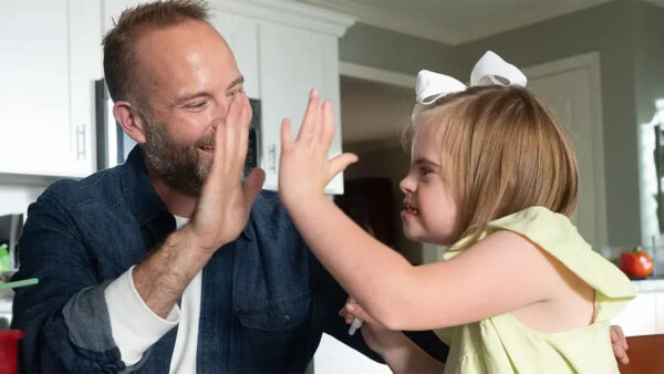 A dad high fives his daughter with Downs syndrome