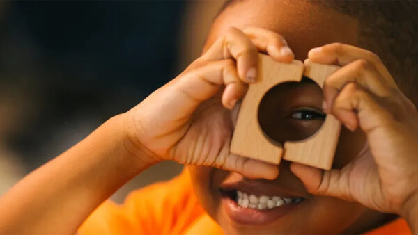 A young boy proudly holds up a wooden block, showcasing his excitement.