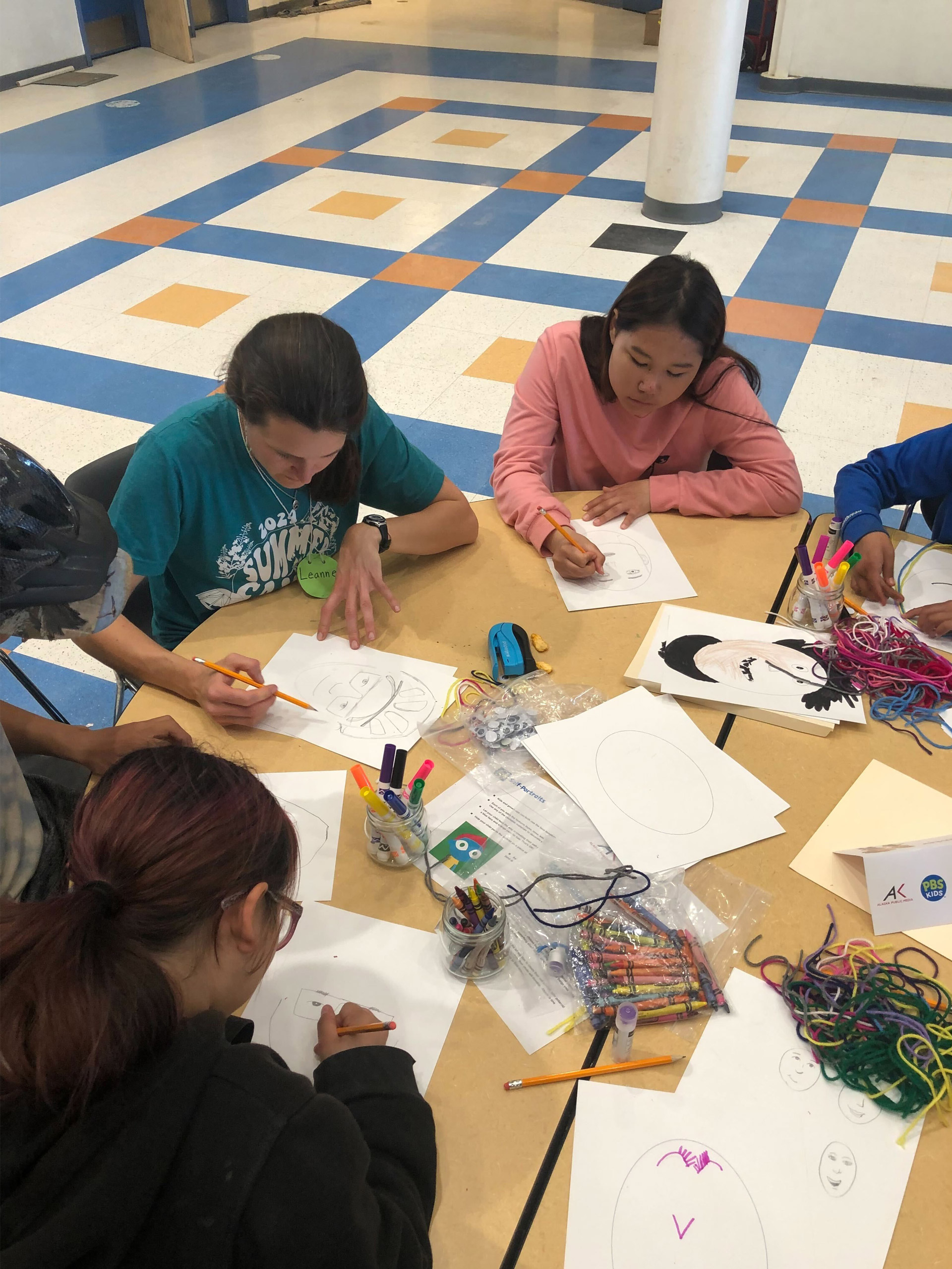 A group of children attentively seated around a table, engaged in a learning activity with their teacher.