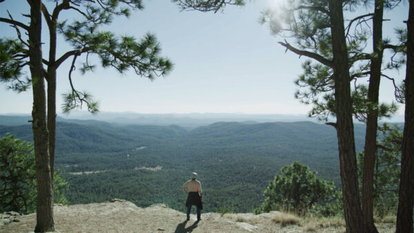 A man stands on the edge of the Mogollon Rim enjoying the view