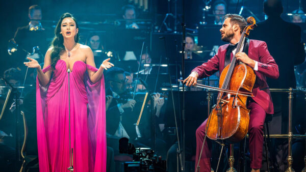 An opera singer performs as HAUSER plays the cello on stage with the Royal Philharmonic Orchestra