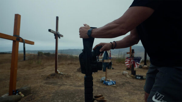 A man holding a gun in a field of crosses