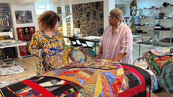 Two woman working on a large blanket