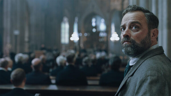 A man from 'Vienna Blood' standing in a church