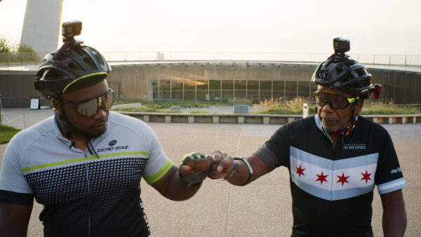 Two men in helmets standing together and fist bumping