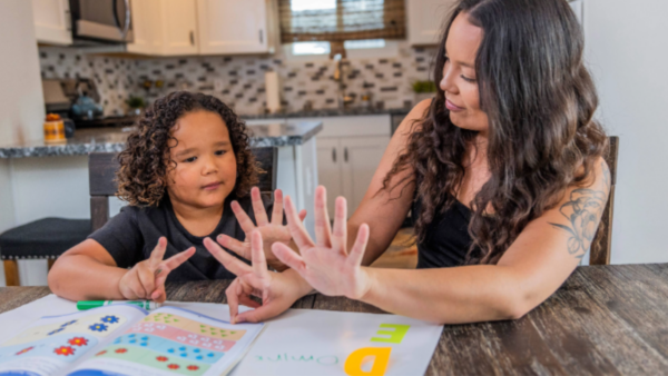 A mom teaching her daughter how to count at their dining room table