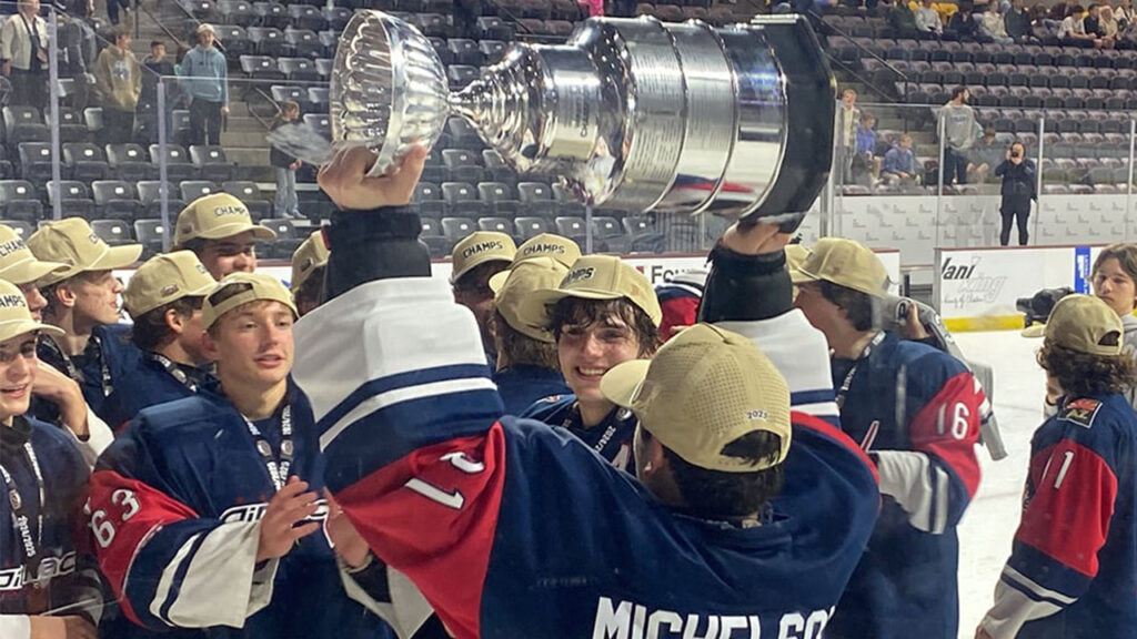A jubilant hockey team proudly holds up the championship cup.
