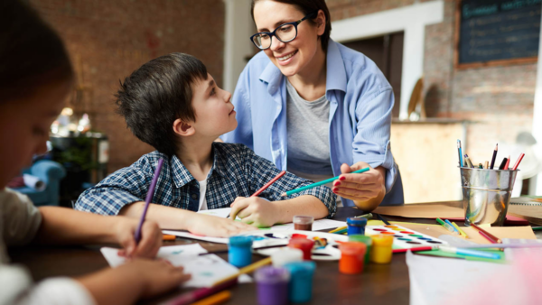 A tired-looking art teacher works with children.