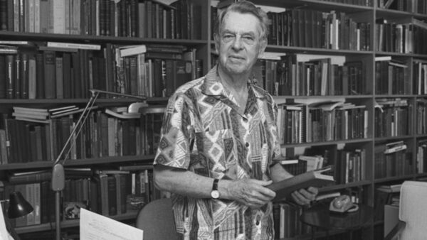 A black and white photo of Joseph Campbell holding a book