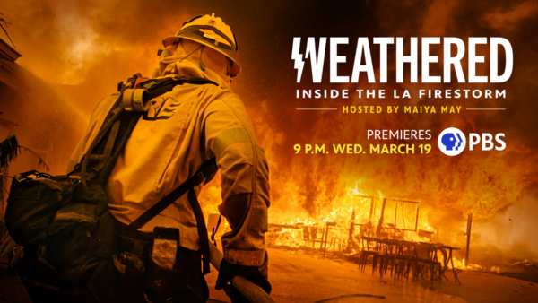 a firefighter in front of a home engulfed in flames