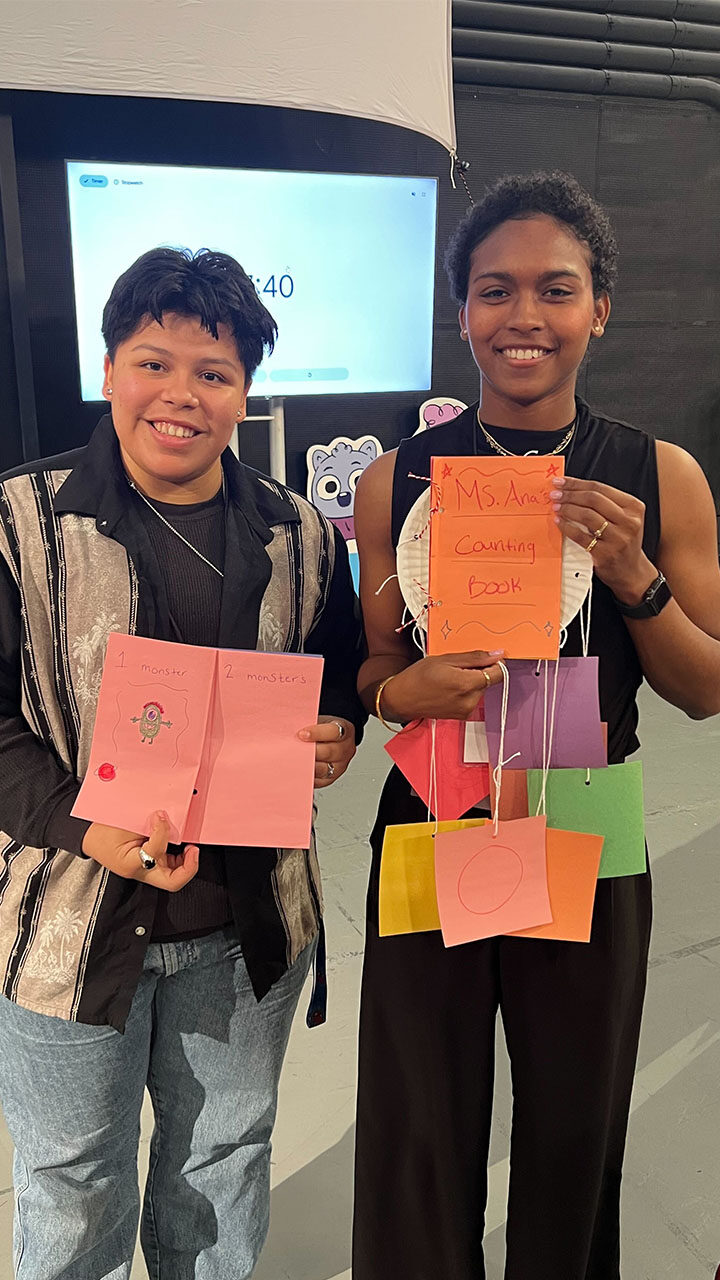 Two young kids smiling while holding up vibrant, colorful cards