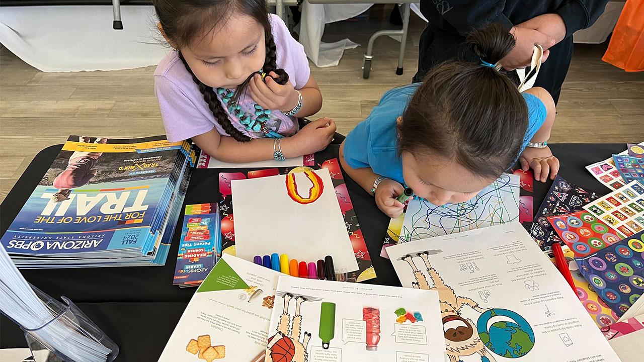 Two kids surrounded by books and art supplies