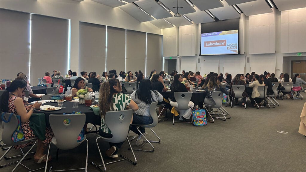 Several individuals gathered around tables in a large room.