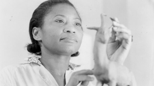 Augusta Savage looking at a small piece of pottery