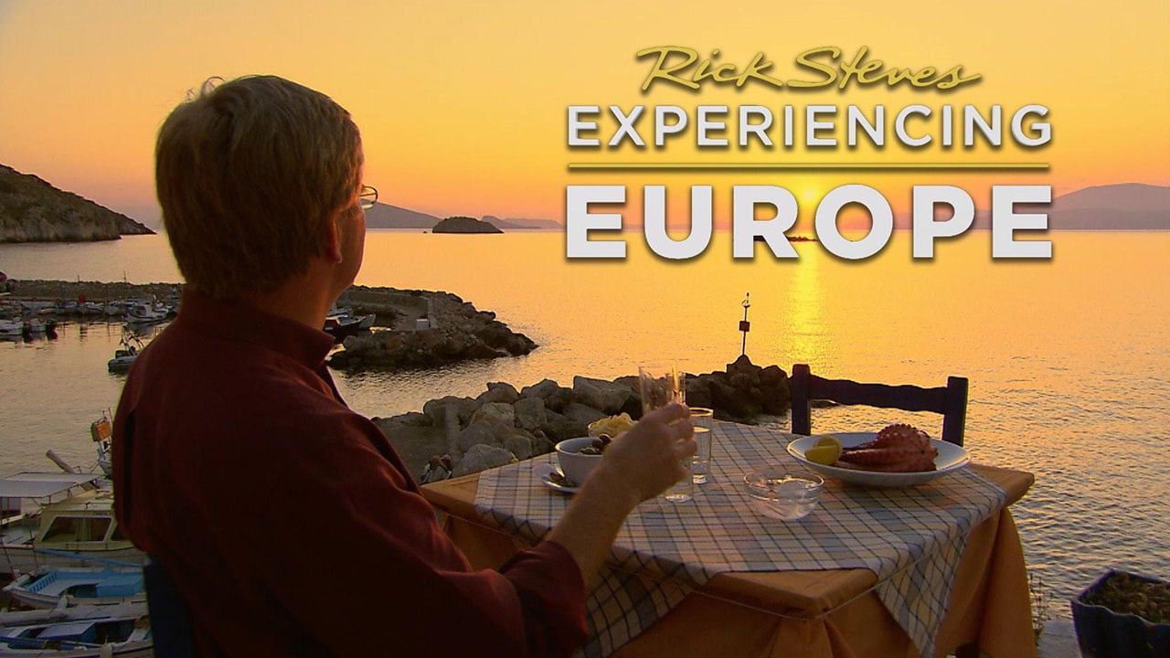Rick Steves sitting at a table in Europe enjoying a sunset