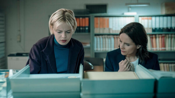 Two detectives in an archive storage room looking at files