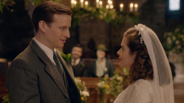A man and woman in wedding attire gaze lovingly at each other