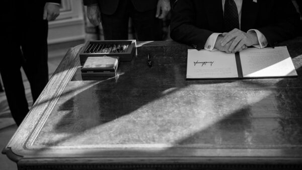 A black and white image of Trump signing a bill