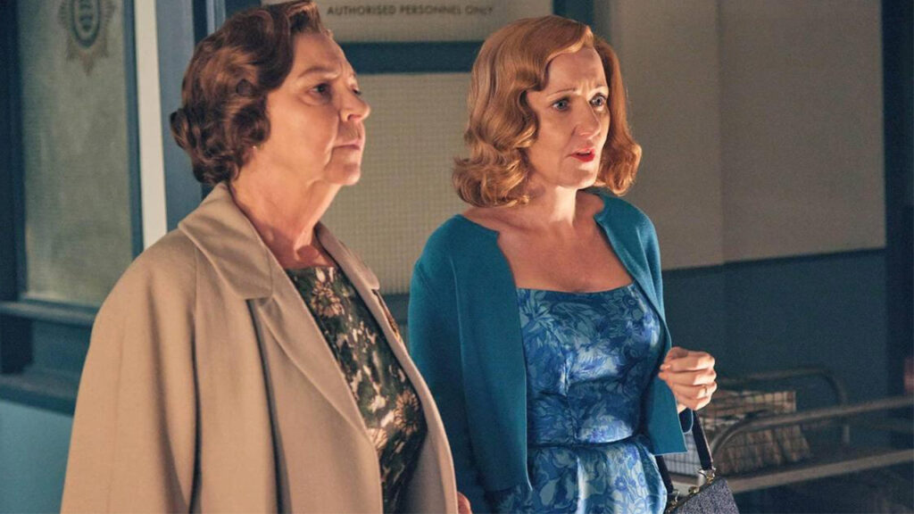 Two women in elegant dresses stand closely together