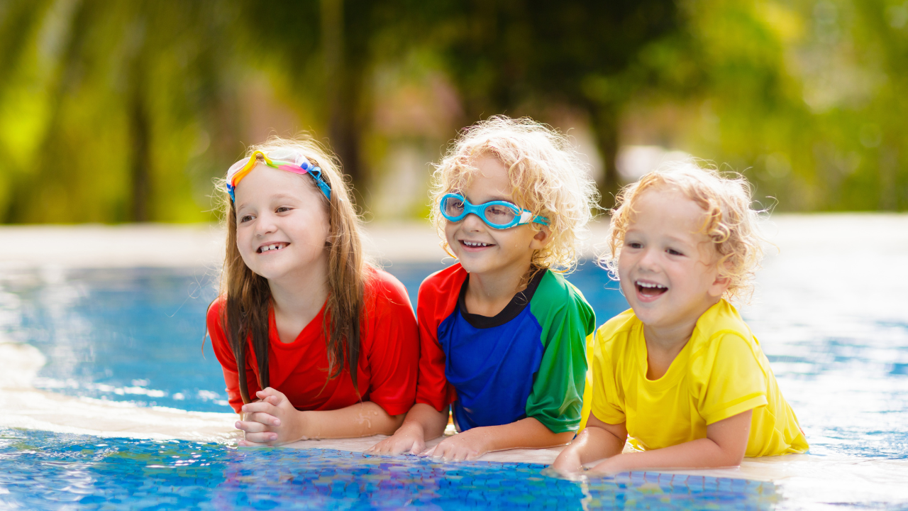 Three kids smiling in a pool