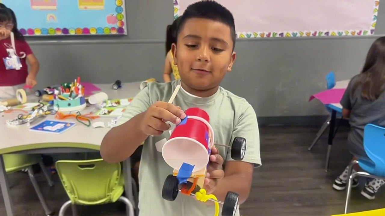 A young boy is focused on crafting a paper airplane