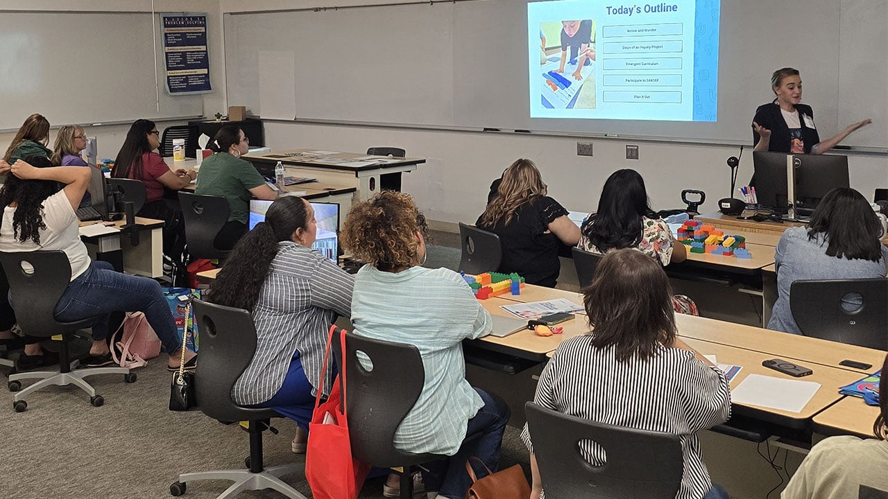 Several individuals at desks in a classroom.
