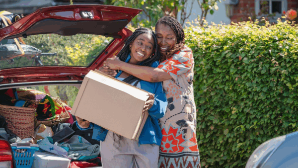 A mom and daughter hugging while packing a car