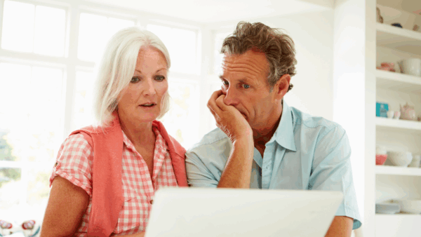 A wife and husband look at a computer