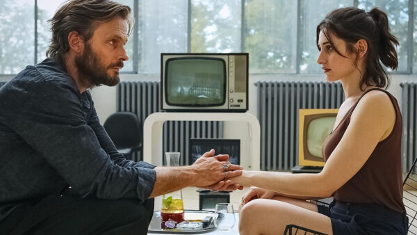 A man and a women holding hands while sitting across from one another