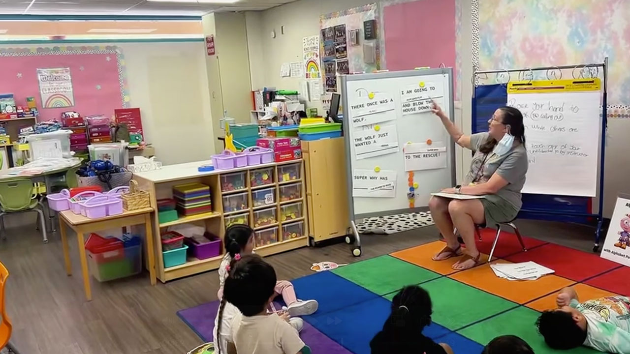 A teacher instructs a group of children in a classroom