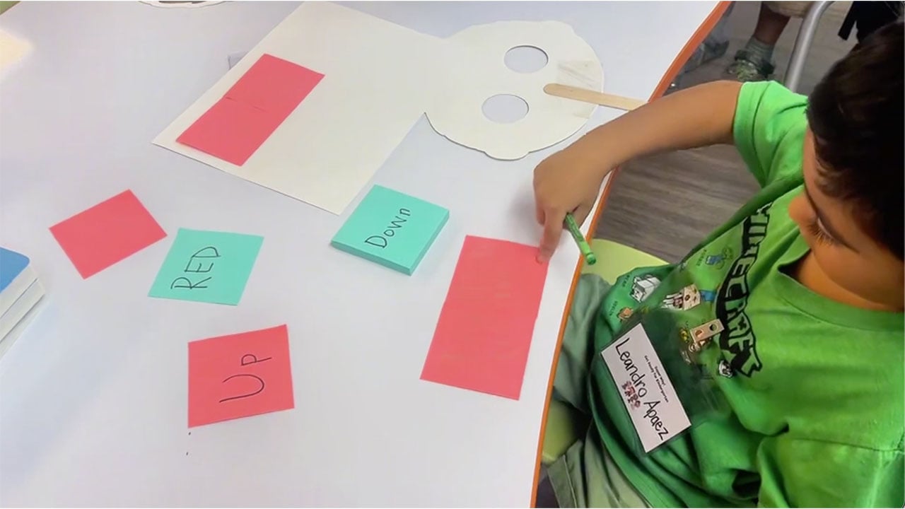 A child is putting colorful pieces of paper on a table.