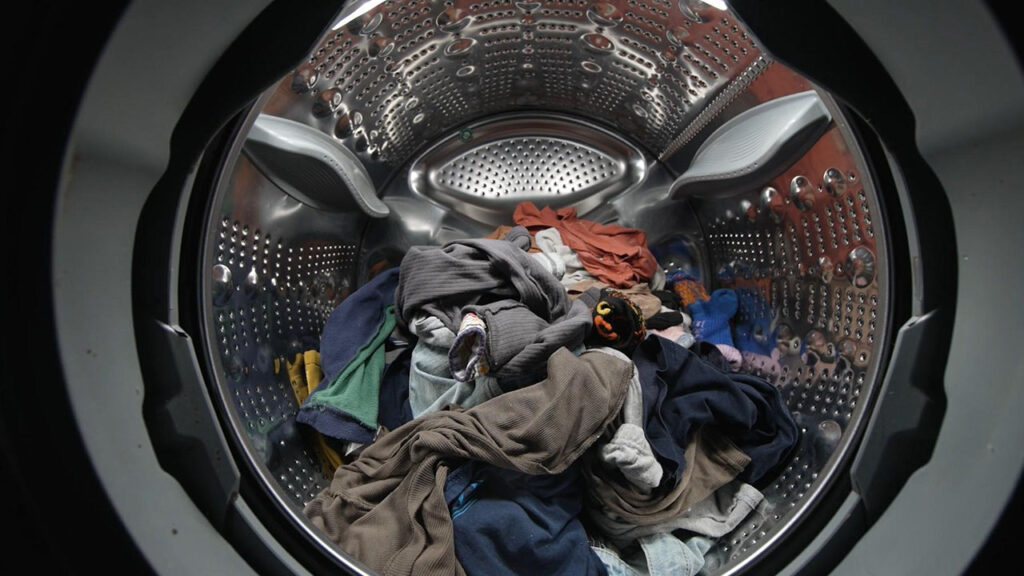A view from inside a washing machine drum filled with clothes