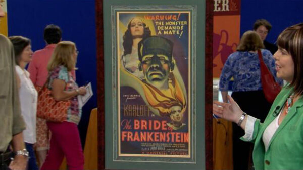 A woman discusses a spooky movie poster with a man.